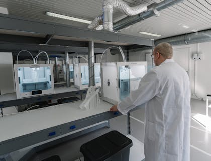 Ein Mann in einem weißen Kittel begutachtet einen 3D-Druck.