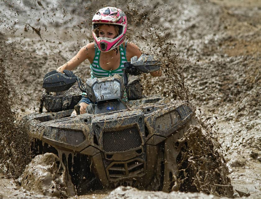 A person riding an all terrain vehicle (ATV) through the mud.