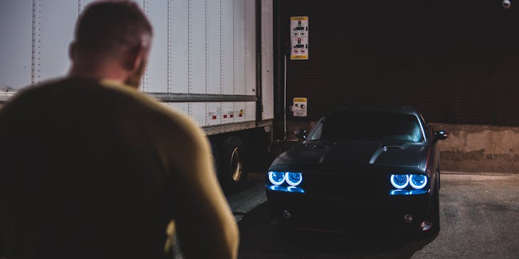 A man approaching a car while unlocking its doors with a remote.