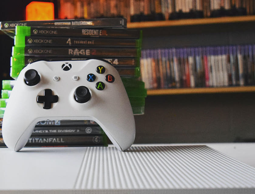 Controle de um Xbox apoiado em uma pilha de videogames em uma loja de video game.
