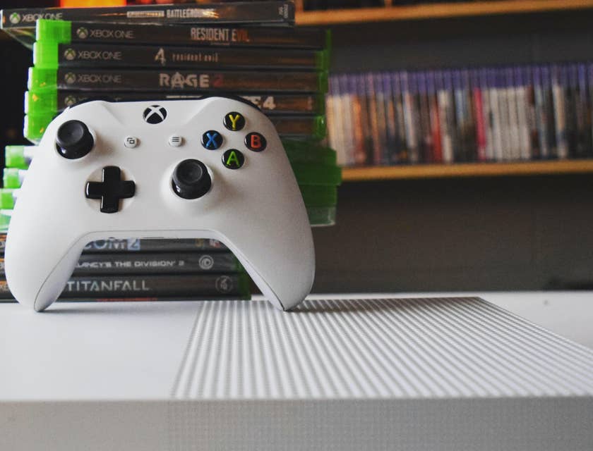 Controle de um Xbox apoiado em uma pilha de videogames em uma loja de video game.