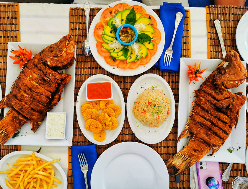 La cuisine des Caraïbes servie sur des assiettes blanches dans un restaurant caribéen.