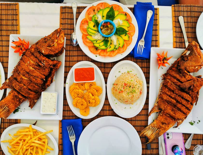 Piatti caraibici serviti su piatti bianchi in un ristorante caraibico.