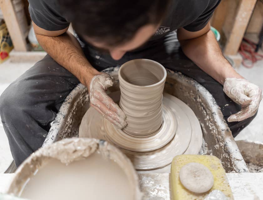 Person shaping a ceramic vase on a pottery wheel.