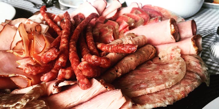 Inviting platter with smoked and cured meat cuts placed on a set table.
