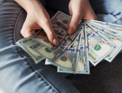 manos de mujer sosteniendo varios billetes en su mano, formando un abanico en un negocio de cambio de cheques y préstamos