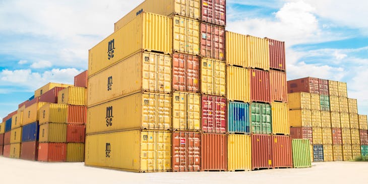 Assorted color shipping containers stacked in a shipyard.
