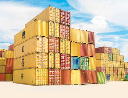 Assorted color shipping containers stacked in a shipyard.