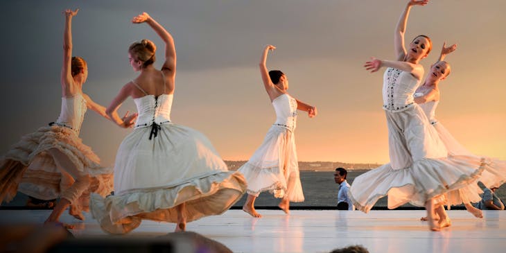 Five ballerinas dancing on stage in dancewear.