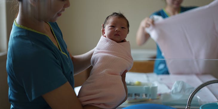 Doula holding a newborn baby.