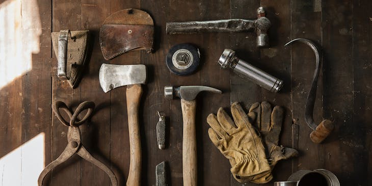 Traditional handyman tools of the trade on a wooden bench surface.