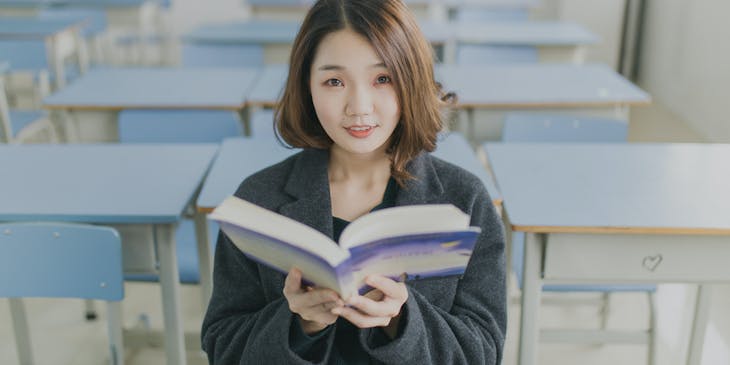 Woman holding open book in a language business.