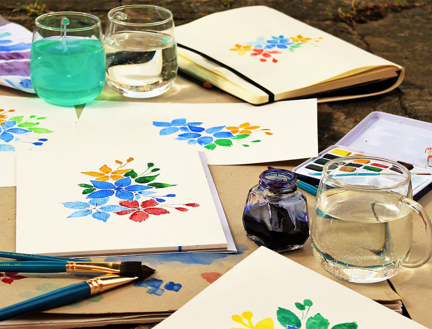 Pinturas de flores coloridas espalhadas sobre uma mesa em uma empresa de pintura com vinho.