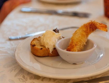 Crostino con baccalà mantecato e un gambero fritto in un piatto in un ristorante veneto.