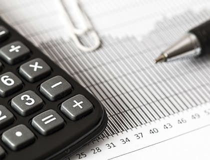 Una calcolatrice, una penna e un foglio per prendere appunti sul modello ISEE sulla scrivania di un CAF o centro di assistenza fiscale.