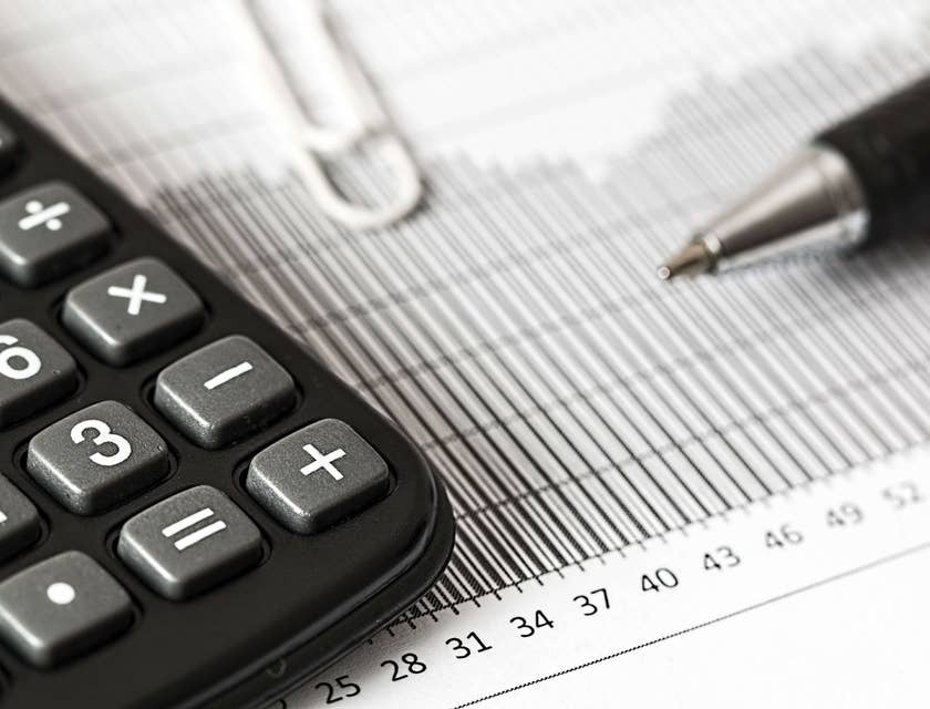 Una calcolatrice, una penna e un foglio per prendere appunti sul modello ISEE sulla scrivania di un CAF o centro di assistenza fiscale.