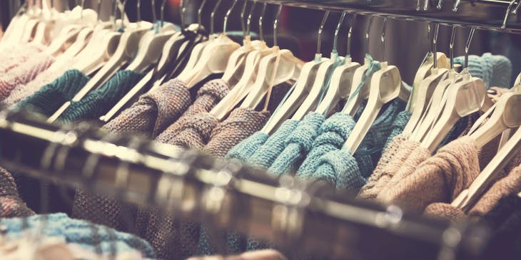 Alcuni capi d'abbigliamento appesi a delle grucce in uno stand di un negozio di abbigliamento.