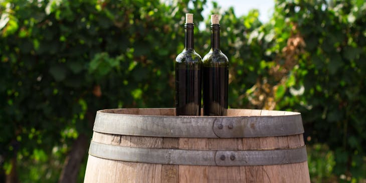Due bottiglie di vino sfuso, o a mescita, sopra una botte nel giardino di un negozio di vini sfusi.
