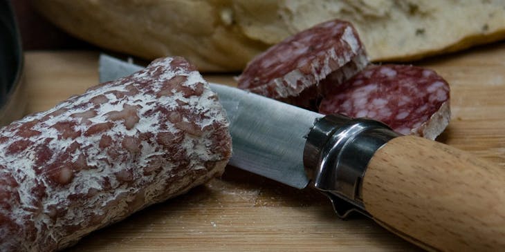 Un salame tagliato a fette sopra un tagliere dentro una norcineria.