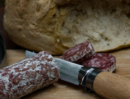 Un salame tagliato a fette sopra un tagliere dentro una norcineria.