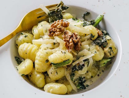 Gnocchi servido em um prato de borda larga em um restaurante italiano.
