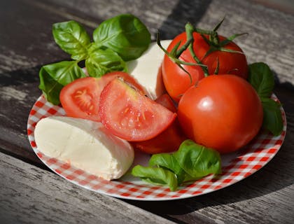 Pomodoro, mozzarella e basilico su un piatto. a quadretti rosso e bianco posto sopra un tavolo di legno.