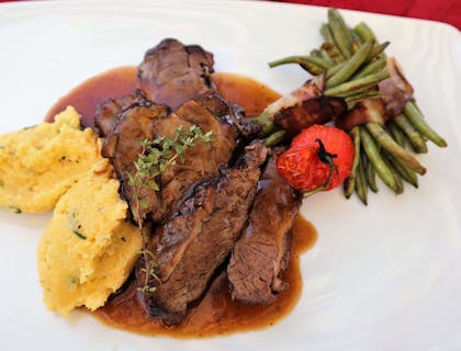 Polenta e brasato di carne serviti su un piatto bianco in un ristorante valdostano.