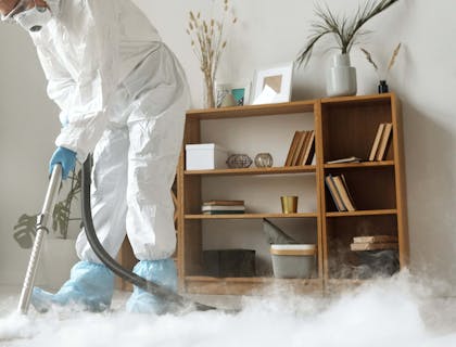 Una persona addetta alla sanificazione che disinfetta un ambiente.