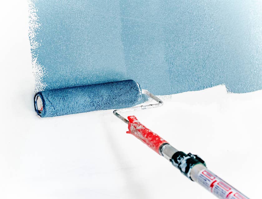 Capa de pintura azul que se aplica a una pared blanca con un rodillo en un negocio de pintura.