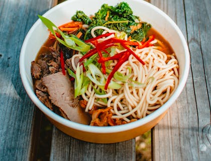Bol de ramen servi dans un bol blanc sur une table en bois.