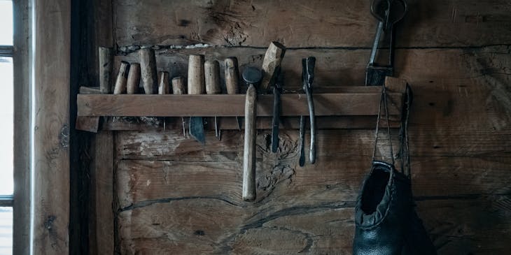 Vintage shoe repair tools hanging in a wooden shed.
