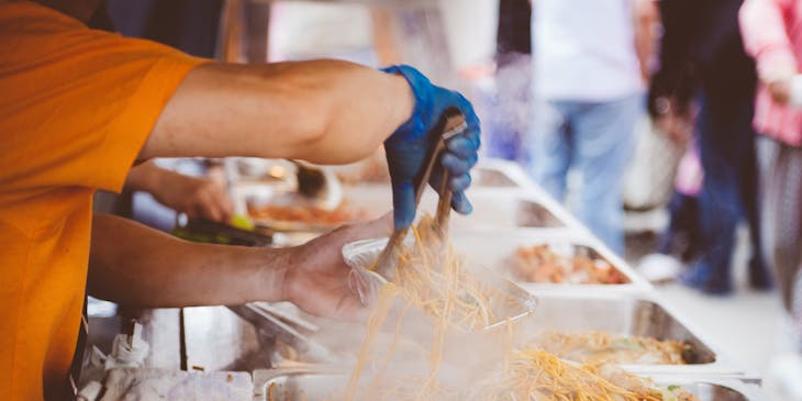 Man preparing street food in a busy outdoor public area.