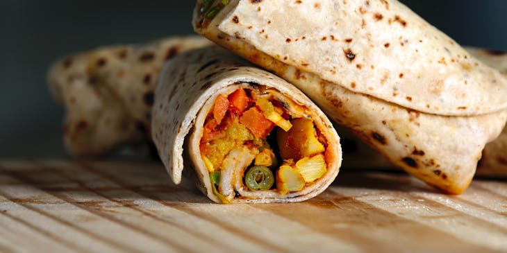 A burrito cut in half on a wooden surface.