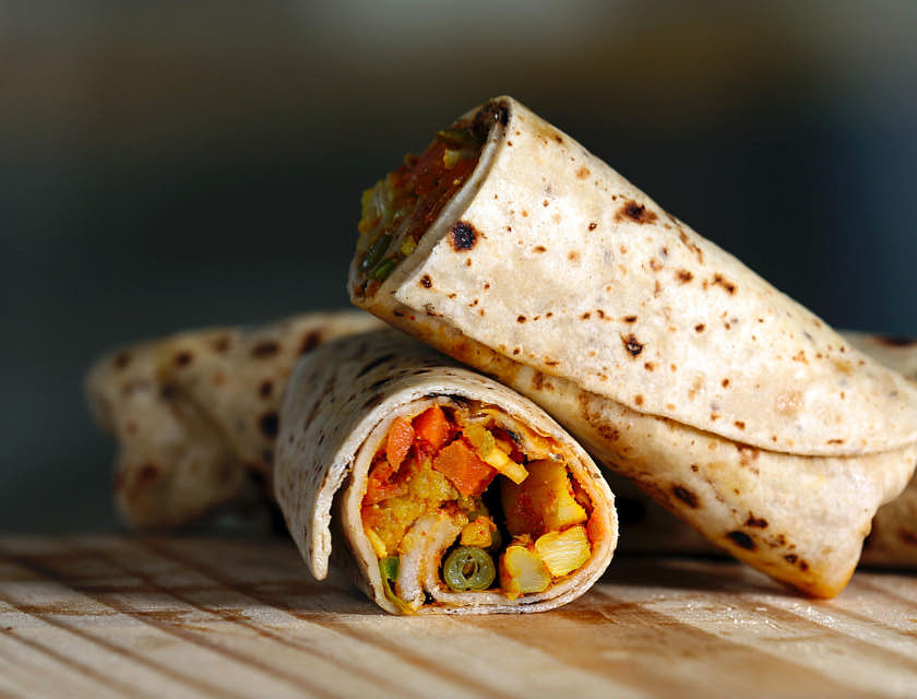 Um burrito cortado ao meio em uma superfície de madeira.