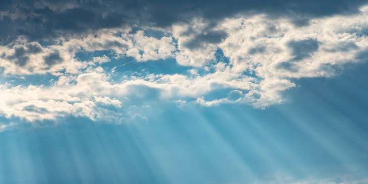 Clouded sky with rays of sunlight shining through.