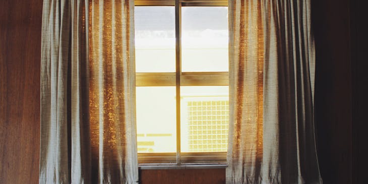 Curtains suspended by a rod framing a window.