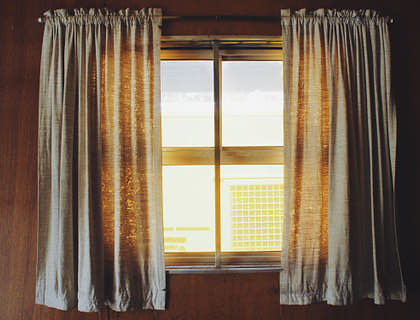 Cortinas suspendidas por una varilla que enmarca una ventana en un negocio de cortinas.