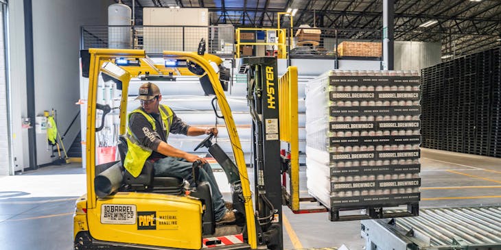 A person loading items using a forklift at a distribution company warehouse.