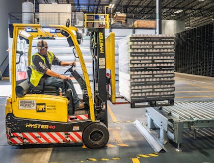 A person loading items using a forklift at a distribution company warehouse.