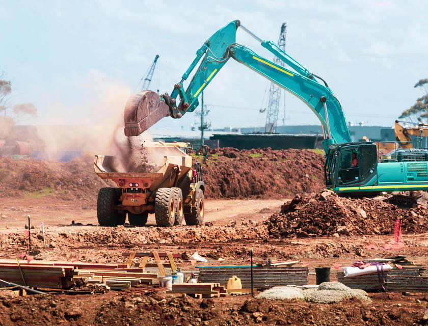 Um caminhão de terraplenagem em um canteiro de obras sendo carregado com escombros.