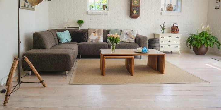 A brown sectional couch against a wall with a coffee table, light, and ornaments around it set up in a home store.