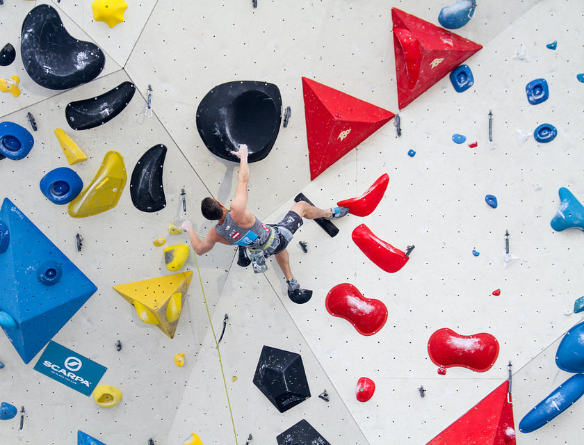 Un homme escaladant un mur dans une salle d'escalade.