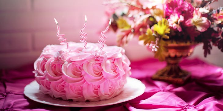 Pink birthday cake with three candles in it.