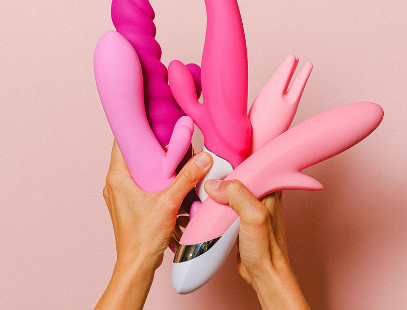 Personne tenant plusieurs sex-toys roses.