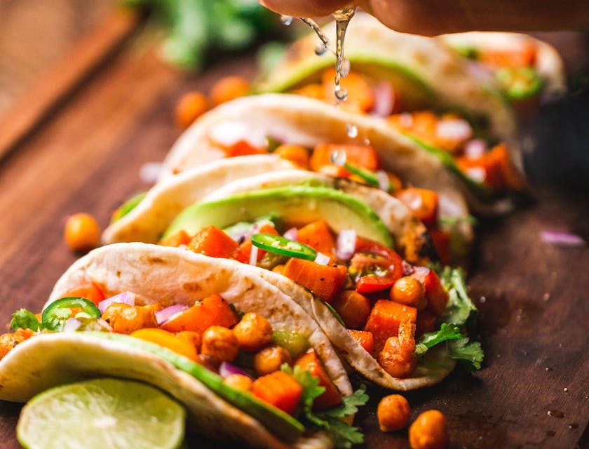 A taco truck chef adding the finishing touches to a tray of tacos.