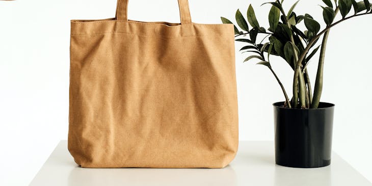 Person holding a tote bag on a table.