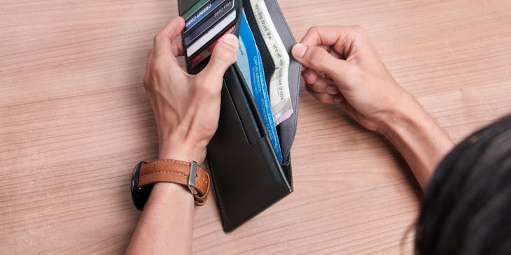 A woman opening a leather wallet.