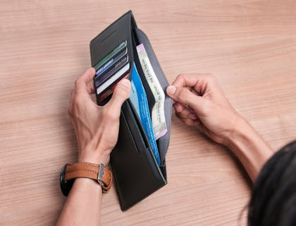 A woman opening a leather wallet.