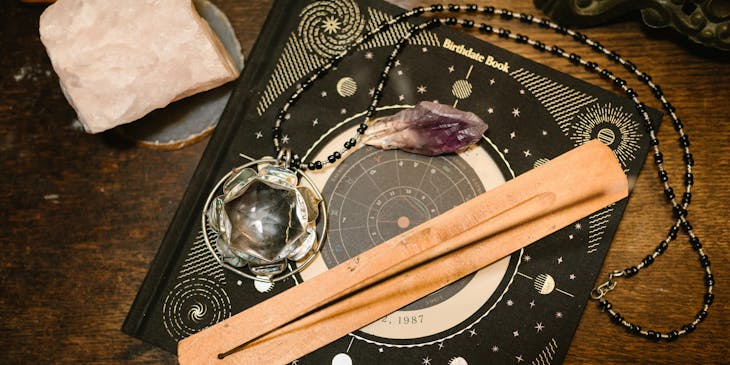 Birthdate book on a wooden table with witchcraft items on top of it.