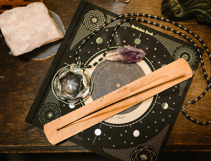 Mapa astral, incenso e cristais em cima de uma mesa de madeira.